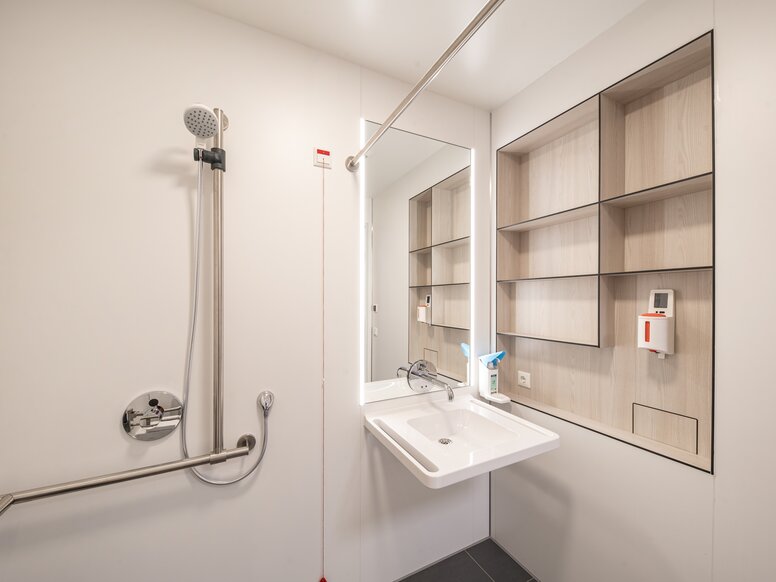 HEWI KARMIN patient bathroom Patient bathroom with washbasin and shower area equipped with a washbasin and a shower holder in stainless steel
