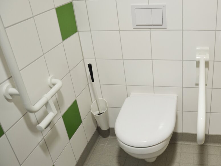 Dom spokojnej starości St Benedikt w Norymberdze Łazienka wyposażona w zestaw szczotek toaletowych, uchwyt kątowy i składany uchwyt pomocniczy